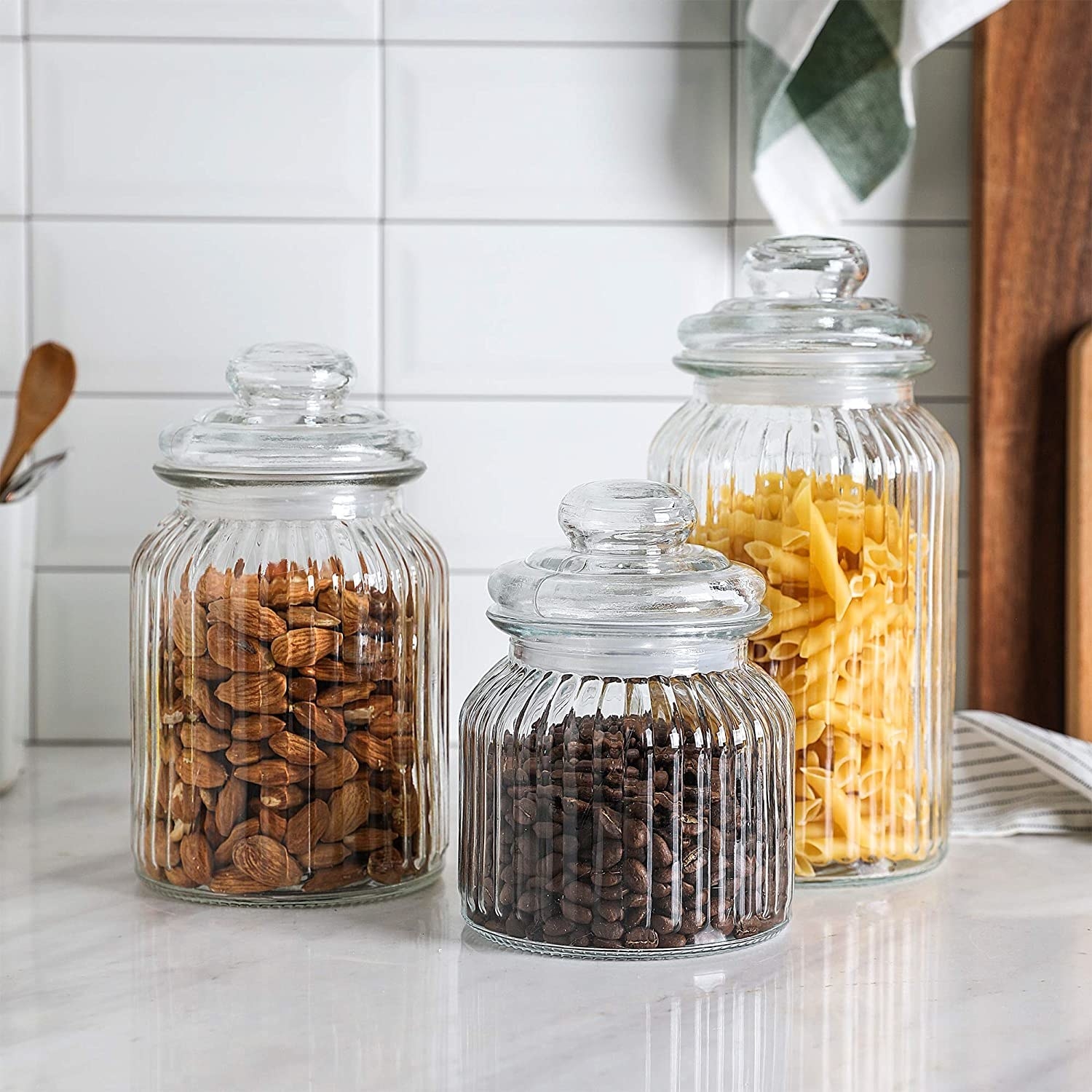 Three jars with nuts, coffee beans, and pasta in them