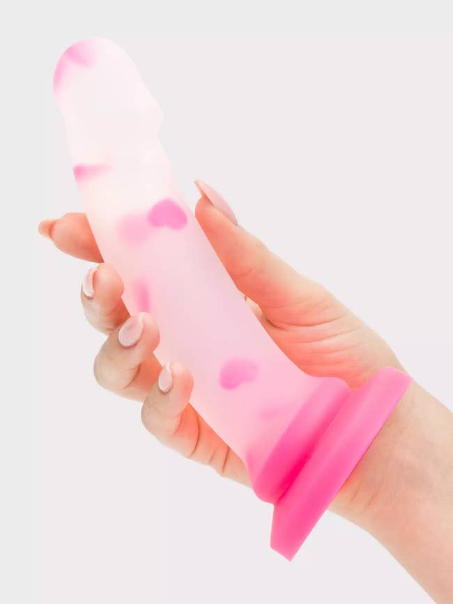 Model holding semi-transparent and pink dildo with confetti hearts