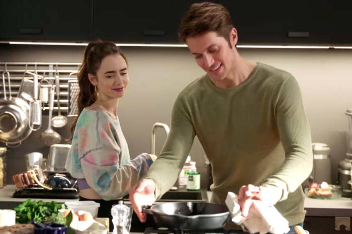 A man cooking in the kitchen with a woman.