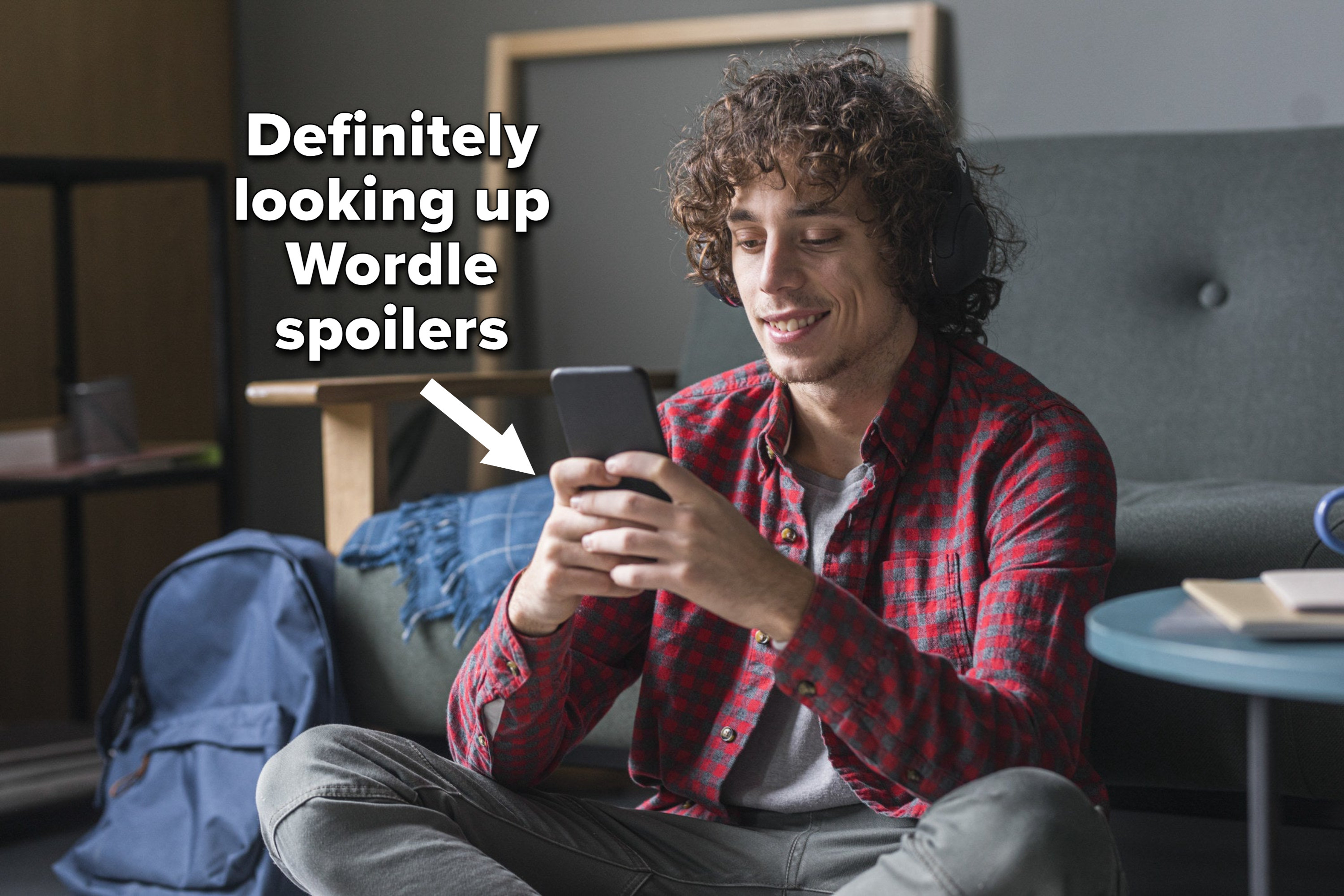A guy sitting cross-legged on the floor looking at his phone with the caption &quot;Definitely looking up Wordle spoilers&quot;