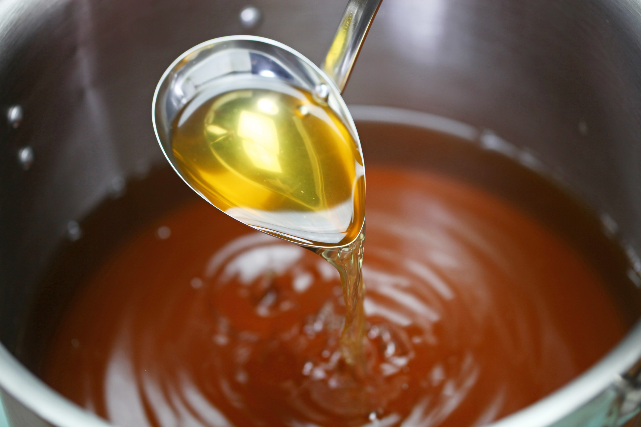 A ladle in a pot of chicken broth.