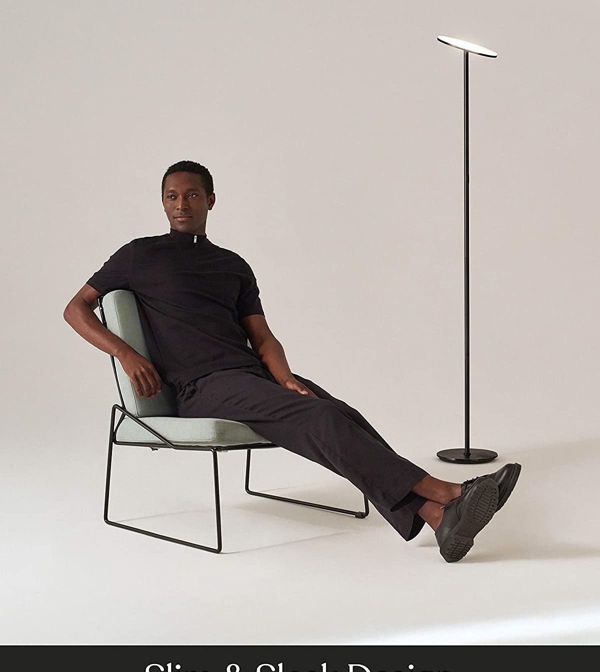 A person sitting on a chair in front of the lamp