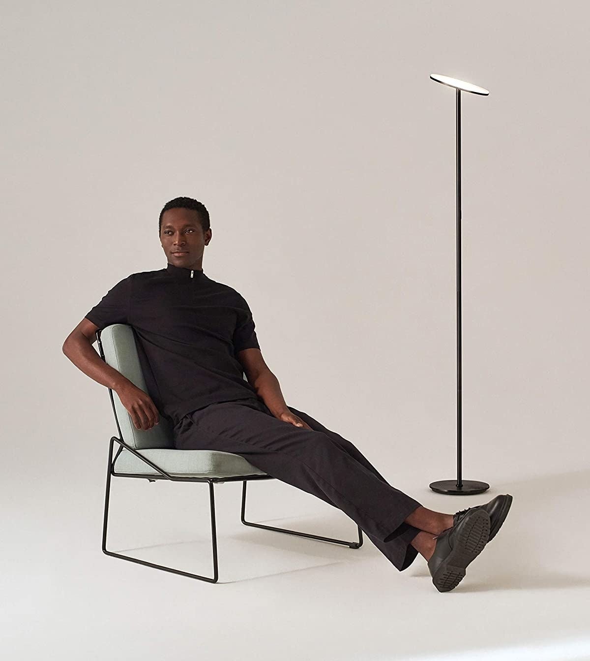 A person sitting on a chair in front of the lamp