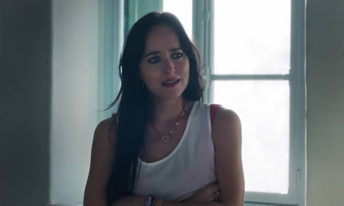 Dakota looks off-camera with a concerned look on her face as she stands by a window