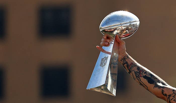 Hand holds up NFL Lombardi Trophy