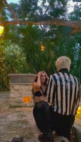 Megan on her knees and holding her head in disbelief as MGK proposes
