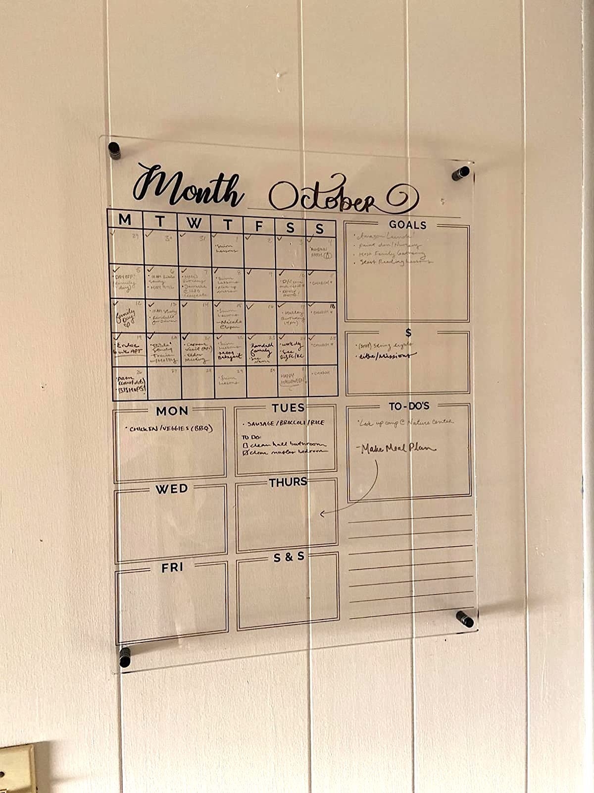 reviewer image of the acrylic calendar hanging on the wall showing a schedule for the month and week and an area for lists and notes