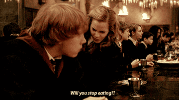 Hermione Granger hits Ron Weasley on the arm with a book as she says, &quot;Will you stop eating&quot;
