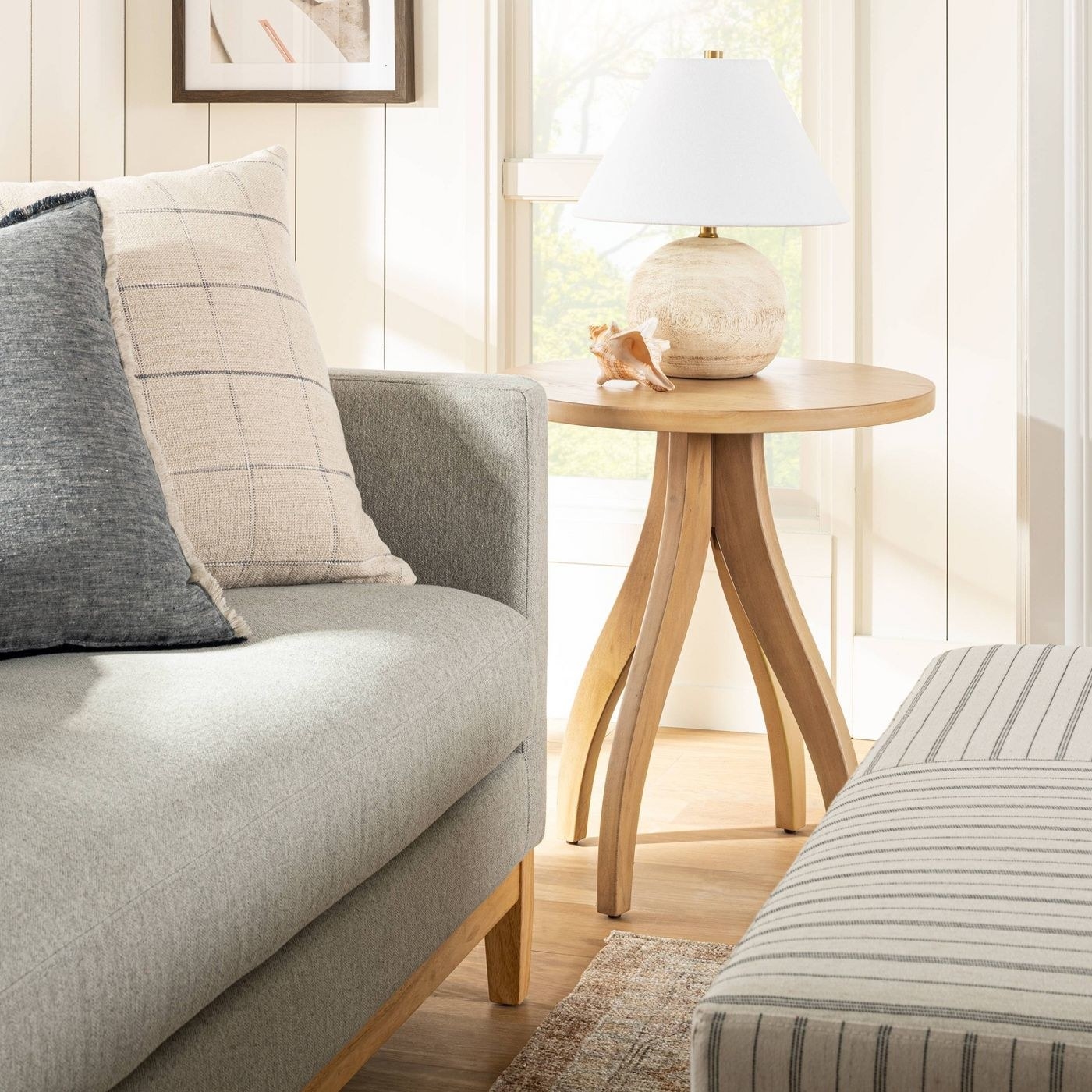 light wood side table with curved legs, next to a gray couch