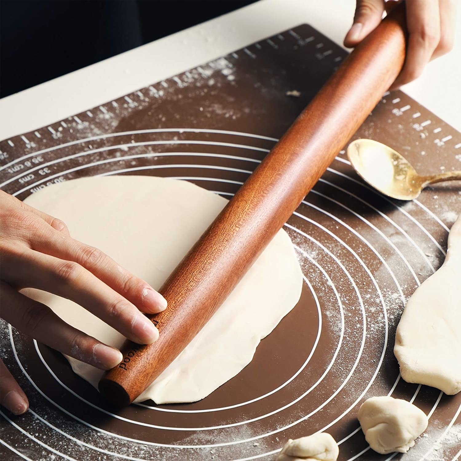 A person rolling out a round piece of dough with the rolling pin