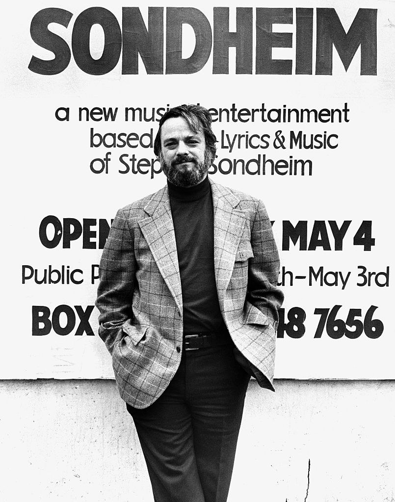 Stephen Sondheim standing in front of one of the posters for his shows