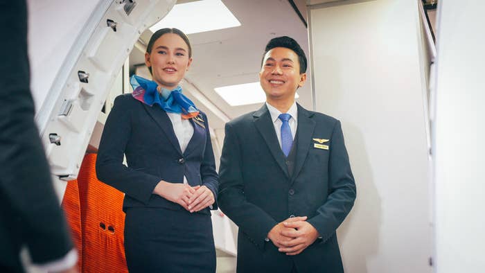 Two flight attendants welcome customers on the plane