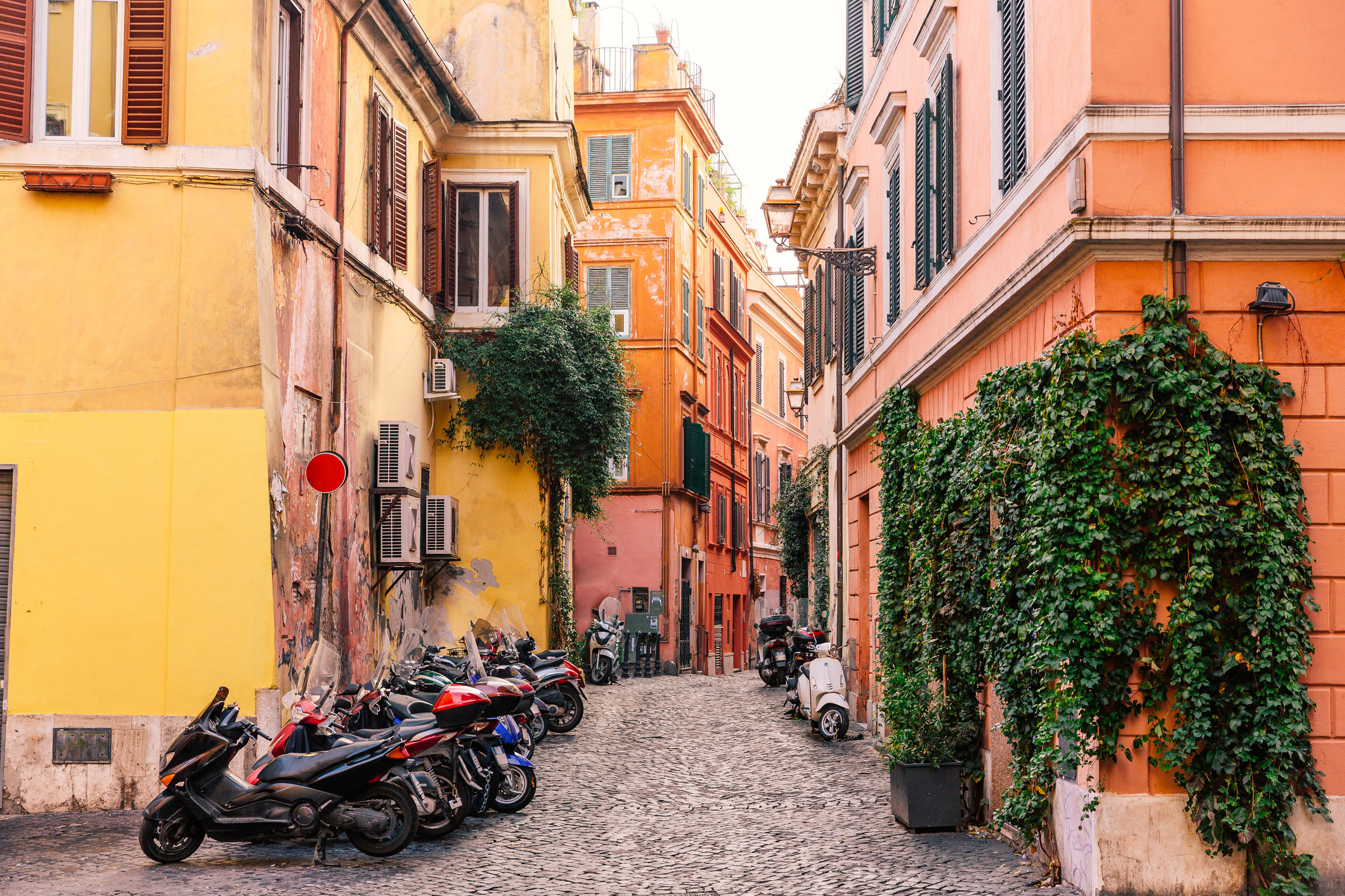 A quiet neighborhood in Rome with colorful buildings and mopeds
