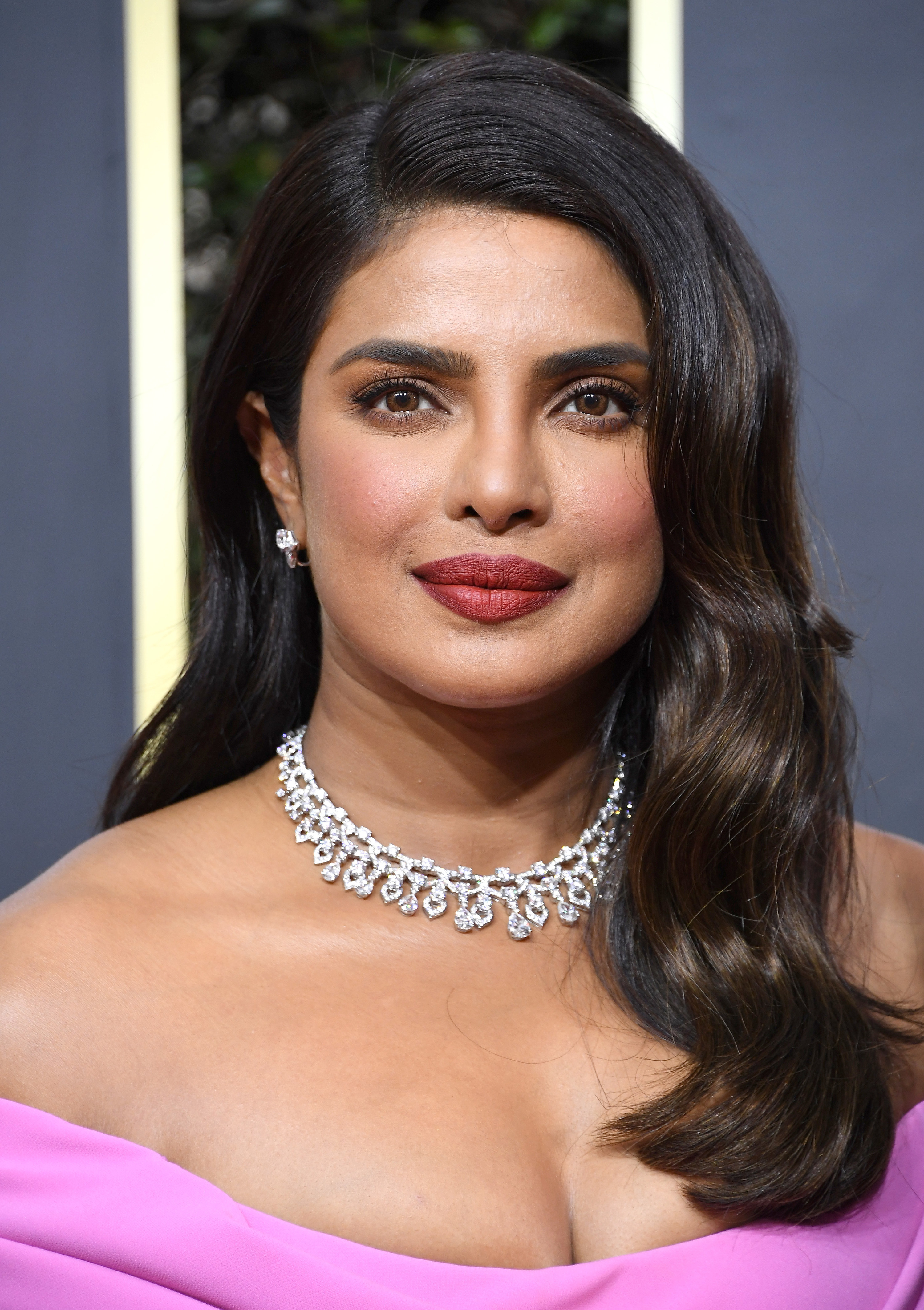 A closeup of Priyanka at a red carpet event where she&#x27;s wearing a diamond necklace and an off-the-shoulder dress