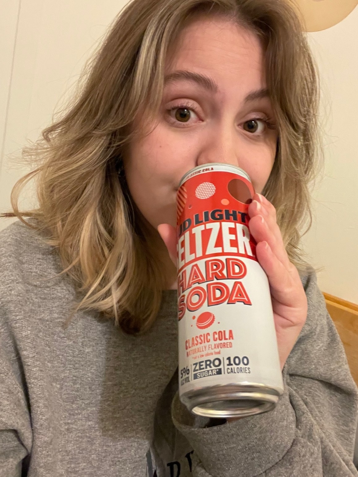woman sipping a hard cola seltzer