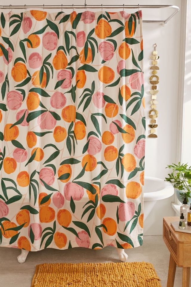 white shower curtain with pink and orange illustrated peaches closed in bathroom