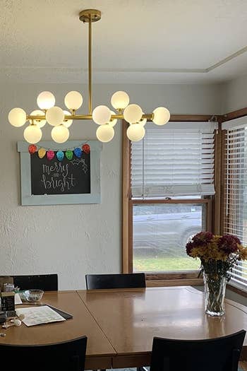 reviewer image of chandelier hung over mid-mod style dining table