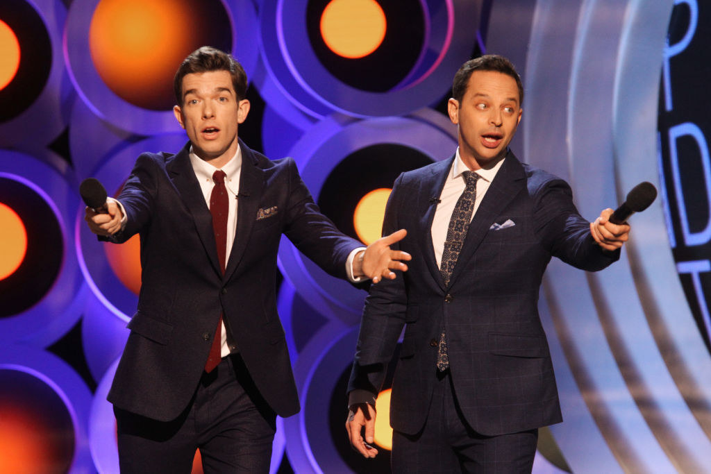 John Mulaney and Nick Kroll in formal suits performing on stage