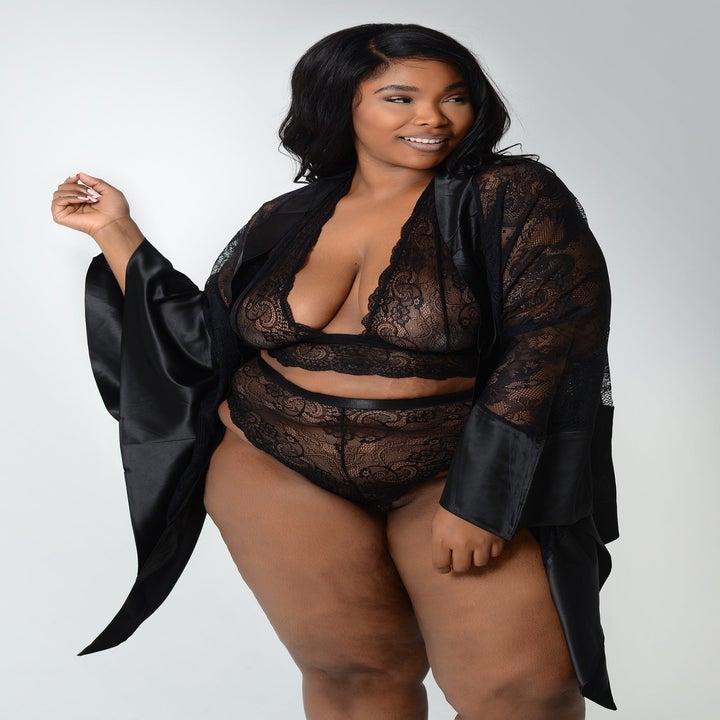 a model wearing a matching lacy bra and underwear set with an open-front black lace robe with long handkerchief sleeves