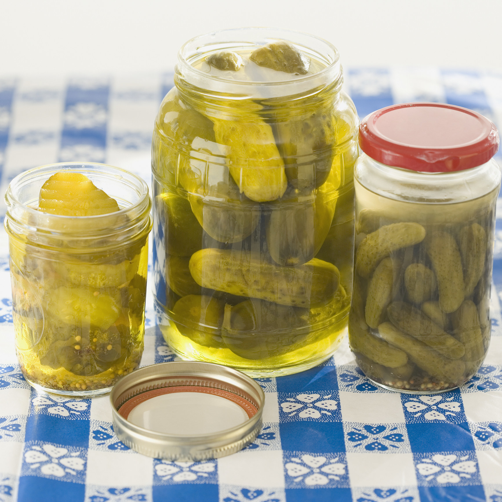 three jars of pickle on a picnic table