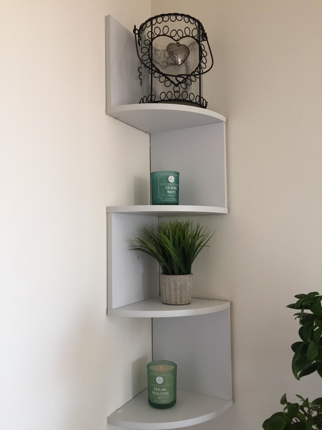 reviewer image of the white shelving unit mounted in a corner of a room