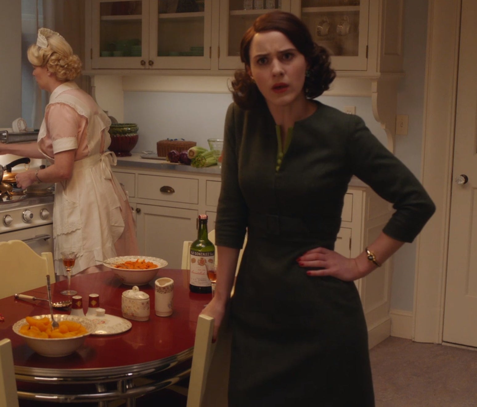 Screenshot from Mrs. Maisel shows Midge in a nice dress standing with her hand on her hip