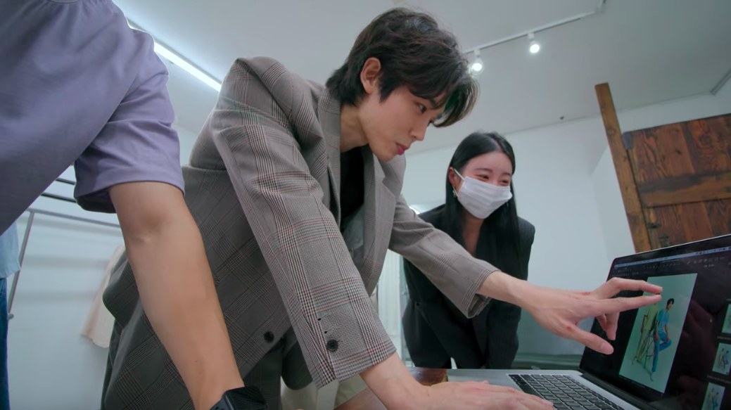 Si-hun points to an image of two fashionably dressed male models on a computer