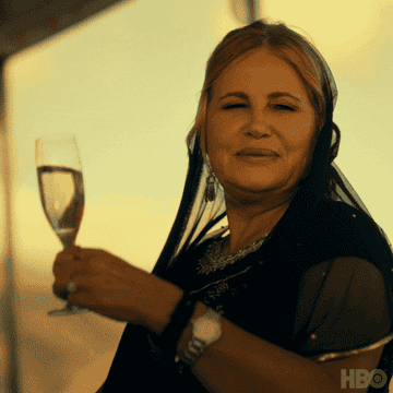 jennifer coolidge raising a glass saying &quot;wee hee&quot;