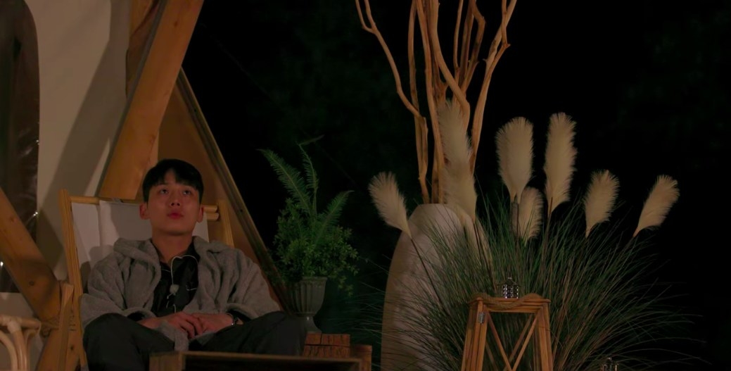 Se-hoon stares up at the night sky on a chair outside the tents