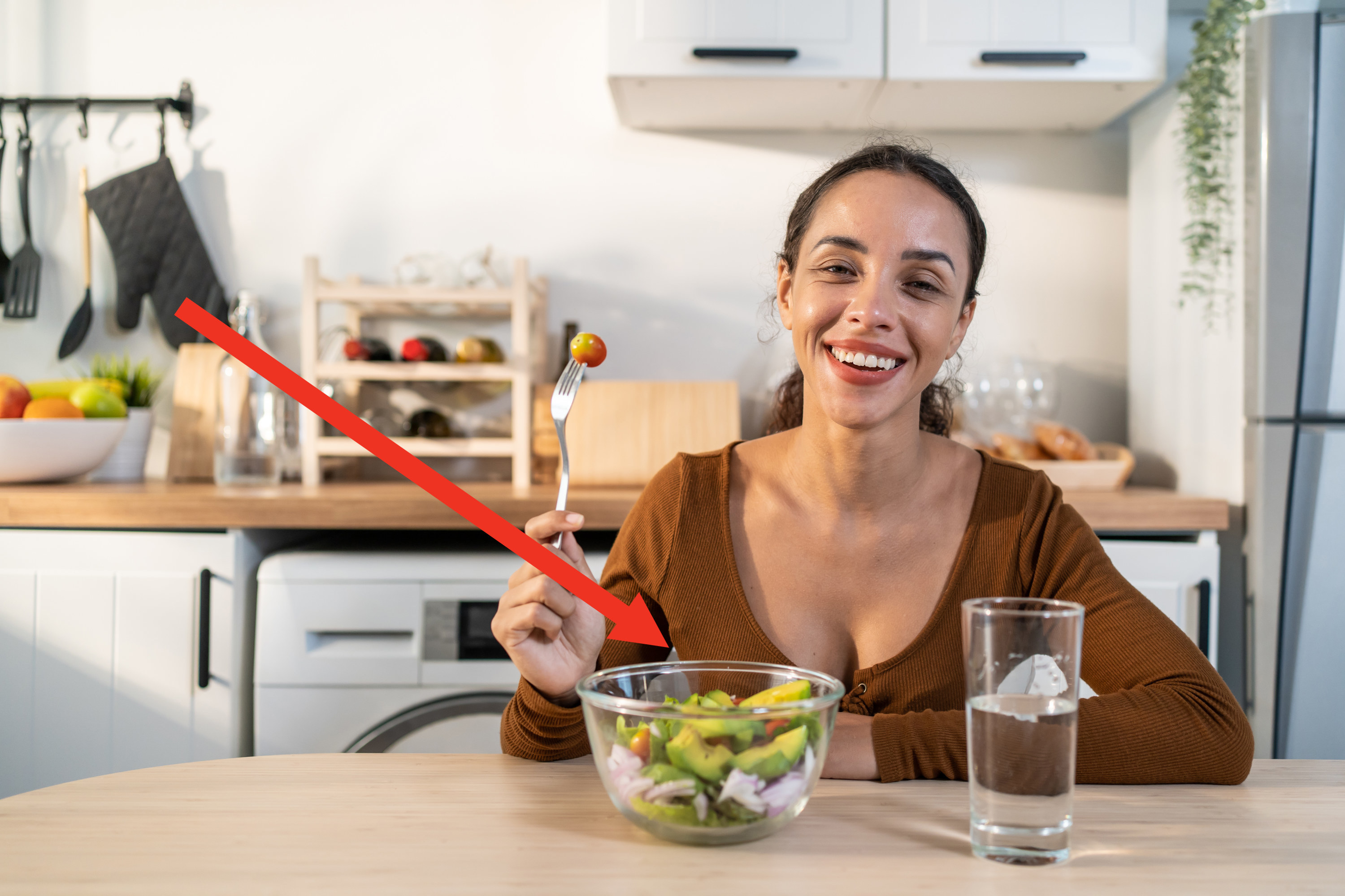 Woman smiling while eating a &quot;healthy&quot; avocado salad and drinking water