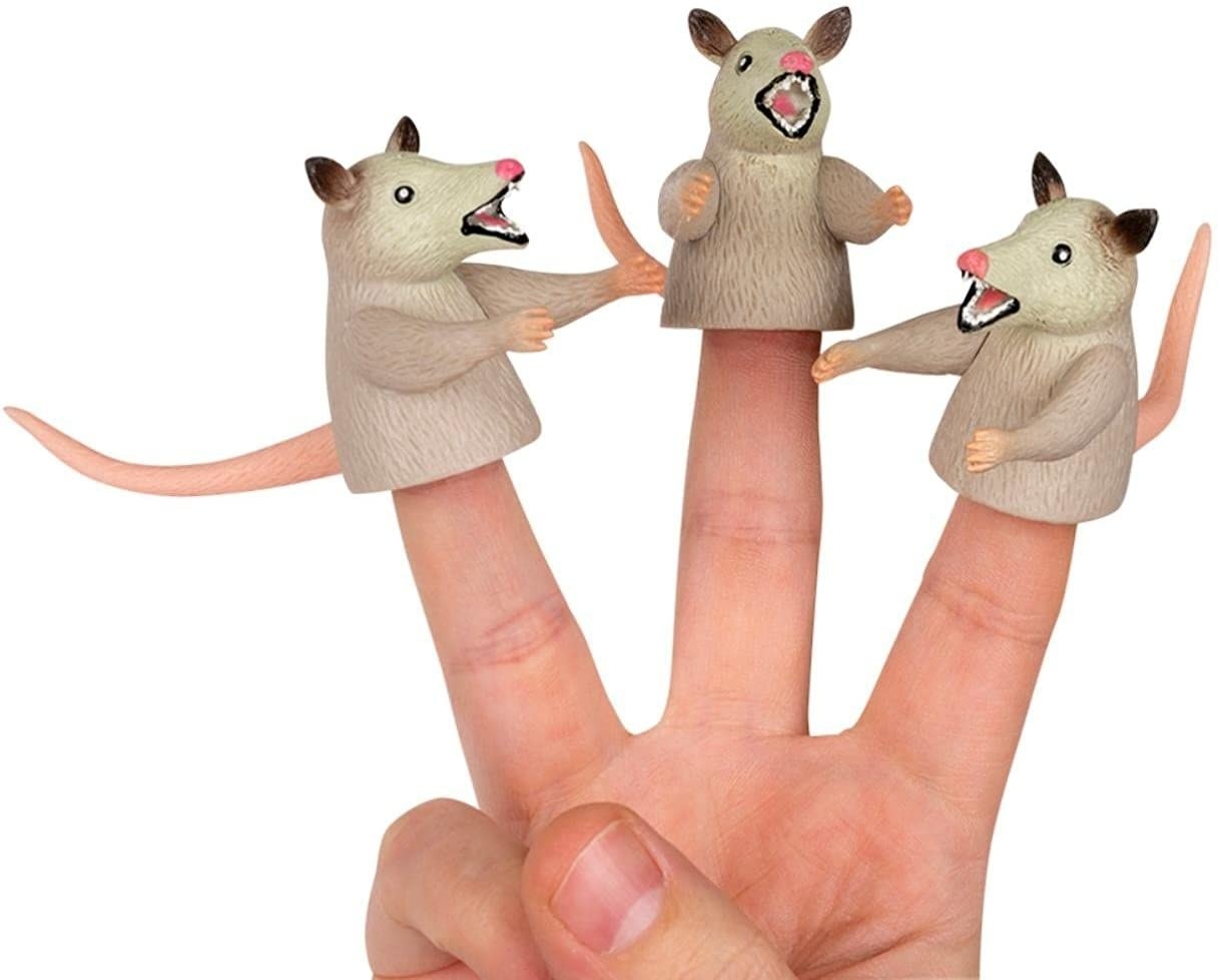 hand wearing three angry opossum finger puppets with arms and tails