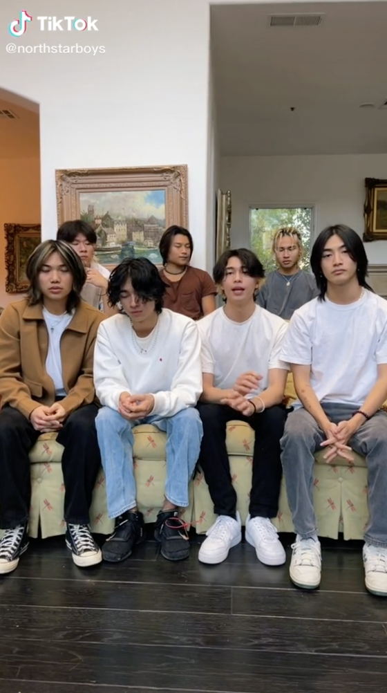 Seven men sitting on a couch facing the camera