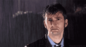 Gif of a man standing sadly in the rain