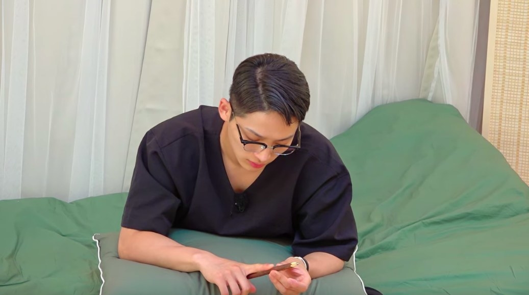 Se-hoon studies a pencil sitting in bed