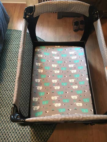 The gray and teal elephant print sheet on their pack-n-play mattress