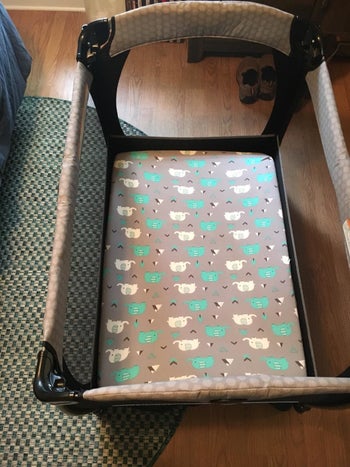 reviewer's photo of the gray and teal elephant print sheet on their pack-n-play mattress