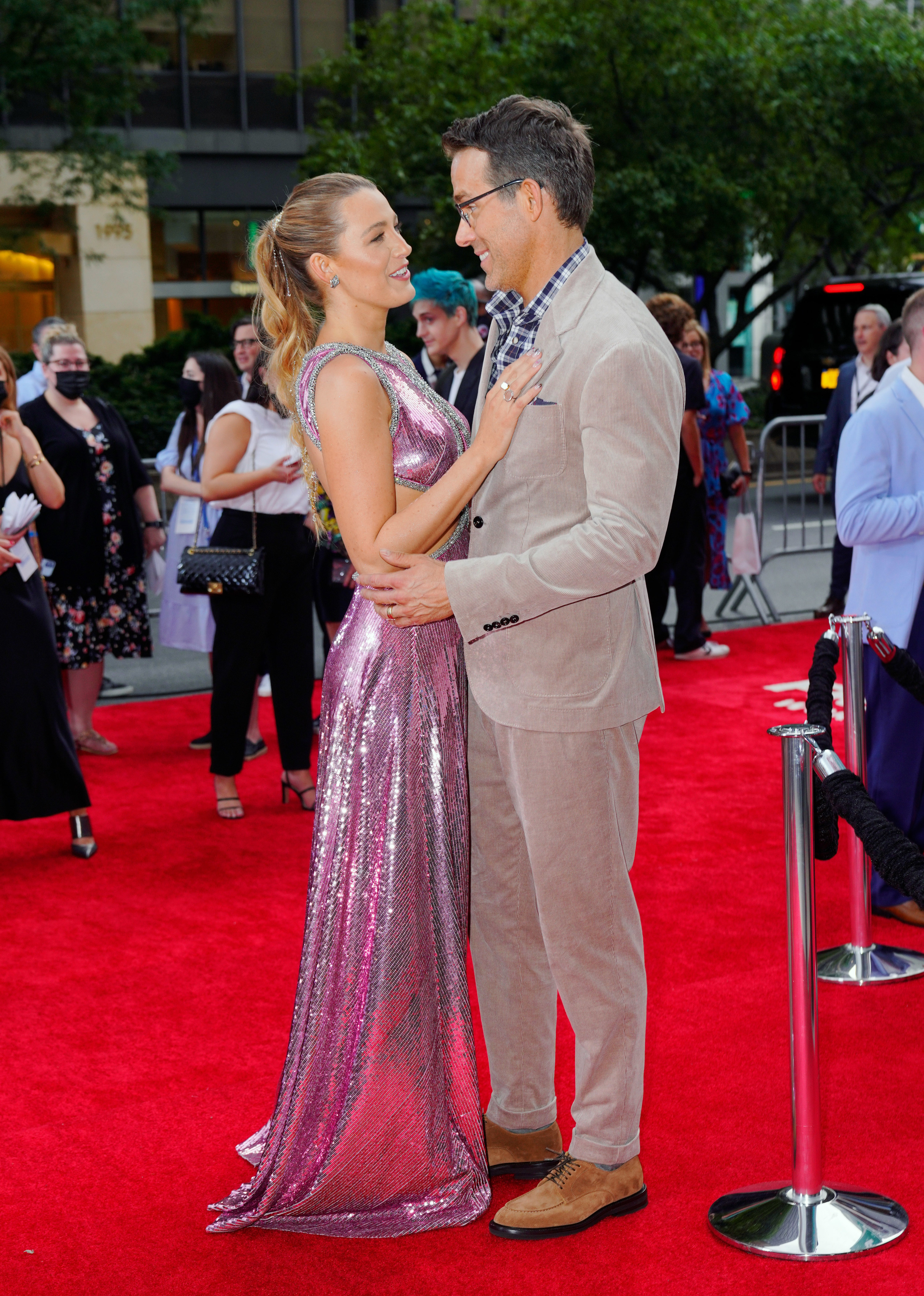 Blake Lively resting her hand of Ryan Reynolds chest, while he holds her at a red carpet premier