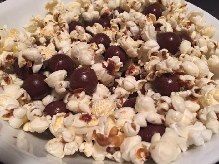 A close up of popcorn that has been mixed with Maltesers