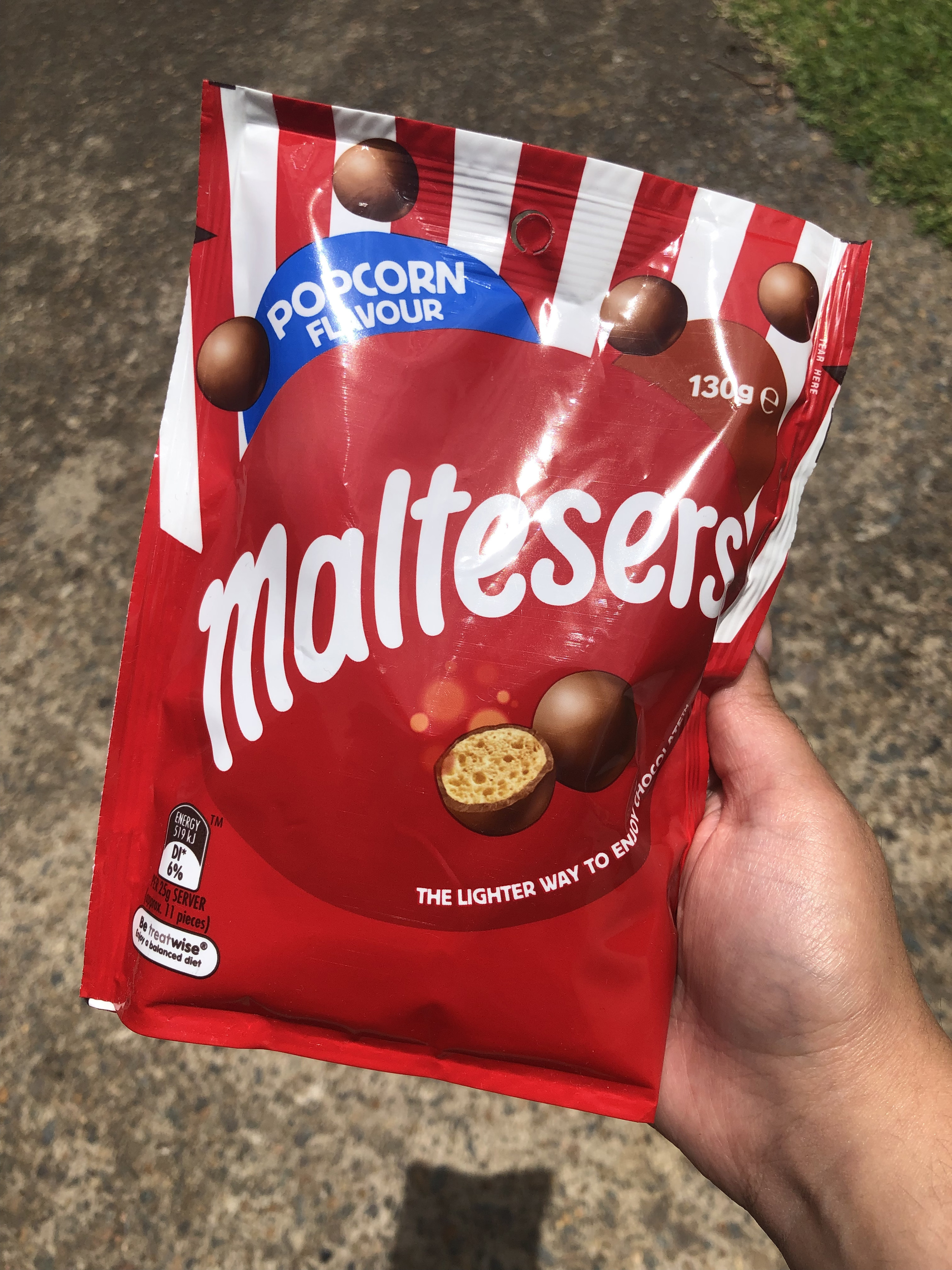 A hand holding a bag of popcorn flavour Maltesers