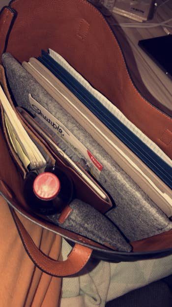 reviewer pic looking into the bag holding a laptop, portfolio, drink, pouches, and more