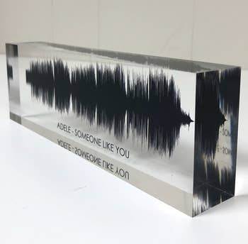 a clear acrylic block with a black soundwave and text reading 