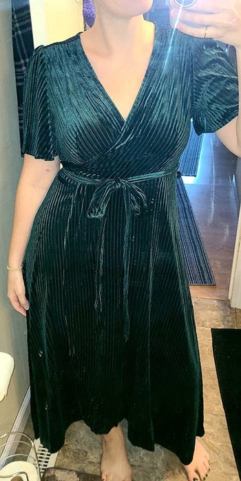 Reviewer photo of them wearing the green velvet wrap dress