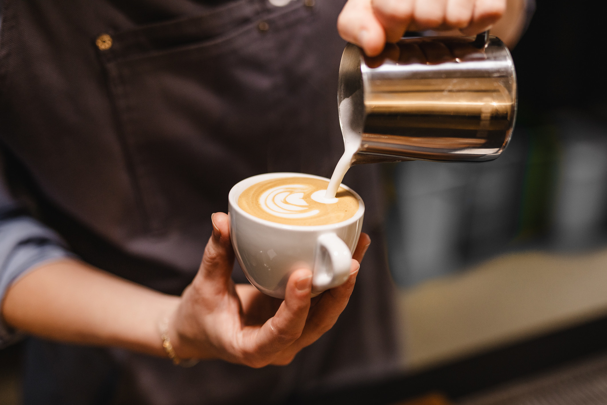 A barista prepares a latte at a coffee shop