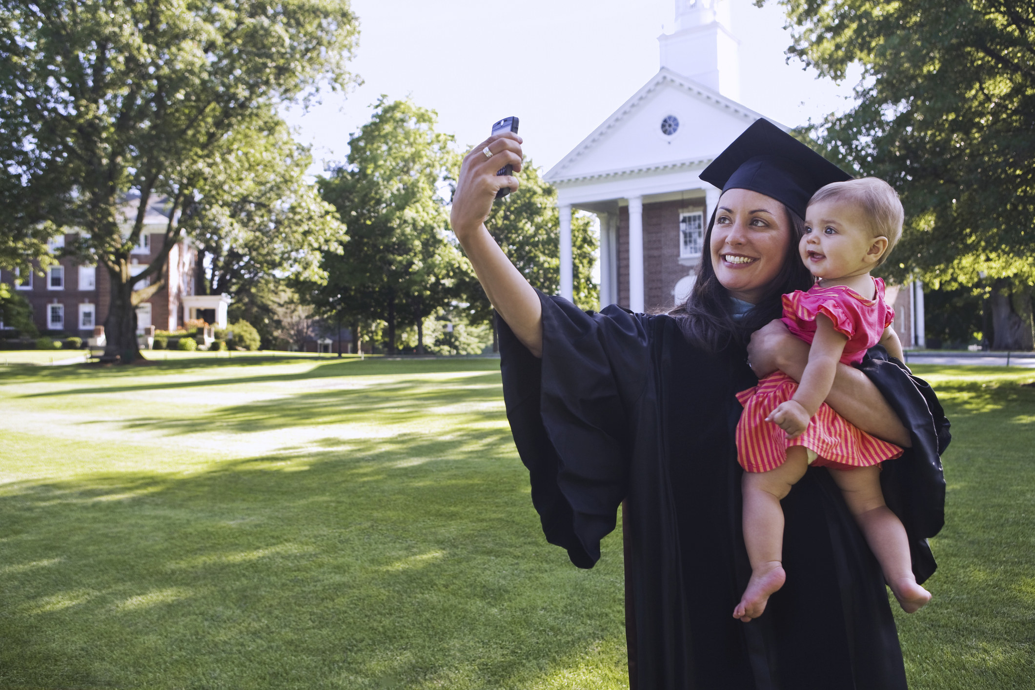College grad taking a picture of herself with baby daughter