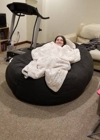 a reviewer curled up on the beanbag with a blanket