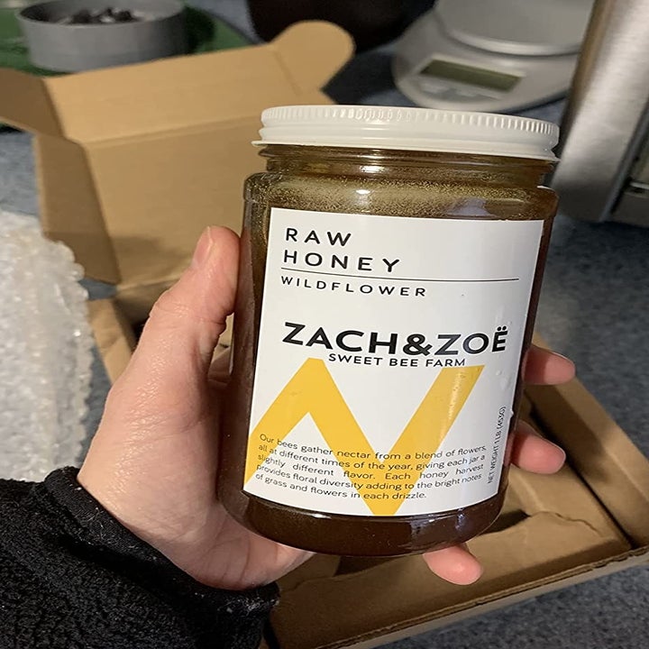 a reviewer photo of a hand holding a jar of wildflower honey