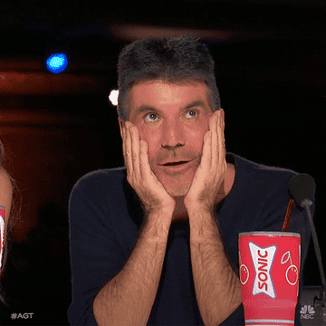 Gif of Simon Cowell with both hands on his cheeks making an expression of surprise