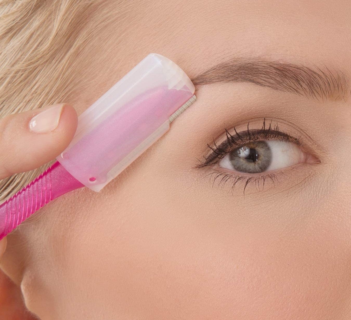 Closeup of someone using a shaver with the precision eyebrow shaping cap on