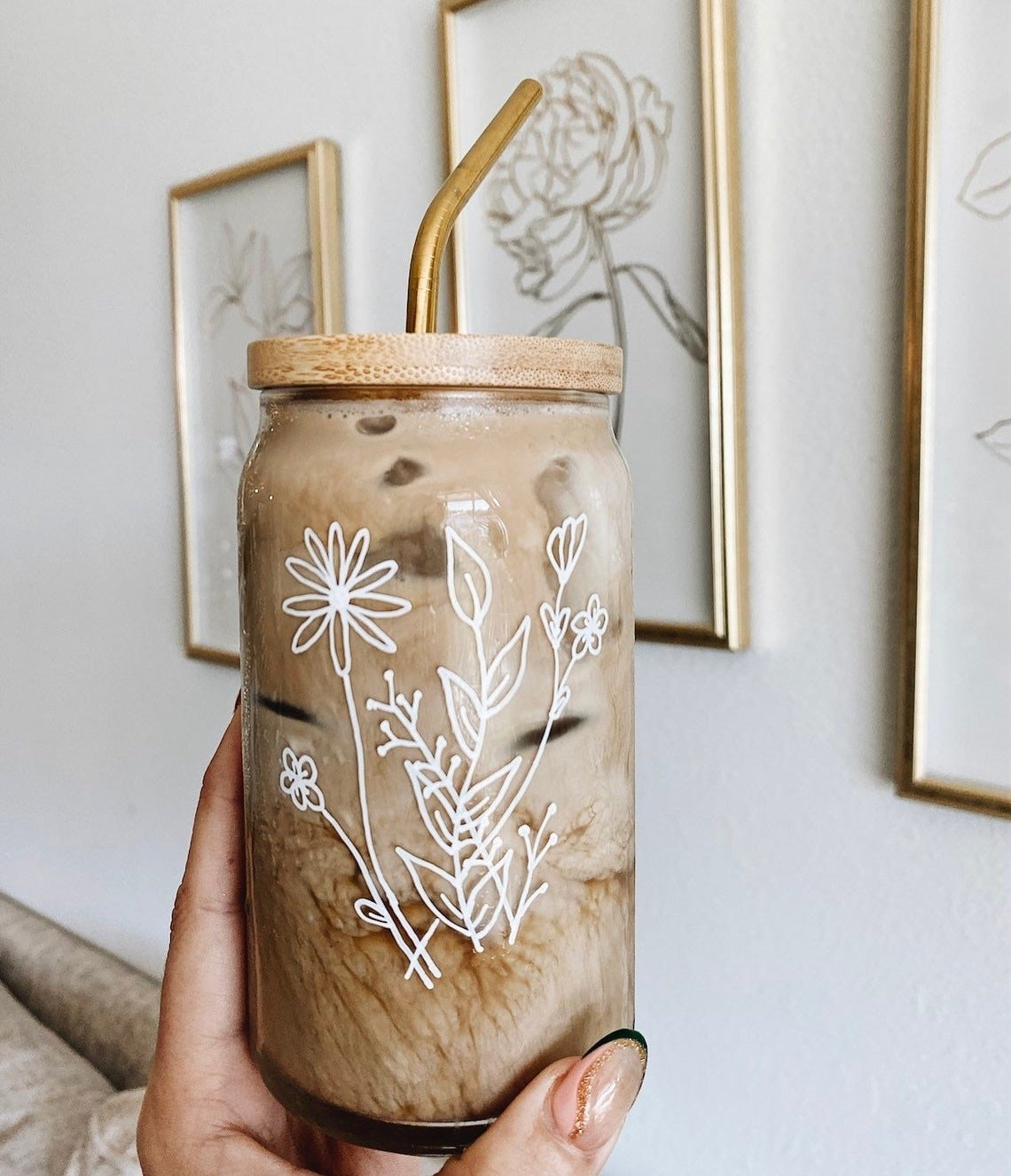 Hand holding the iced coffee glass with floral print