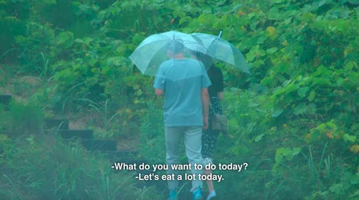Se-hoon and Ji-yeon walk holding umbrellas and say "let's eat a lot today"